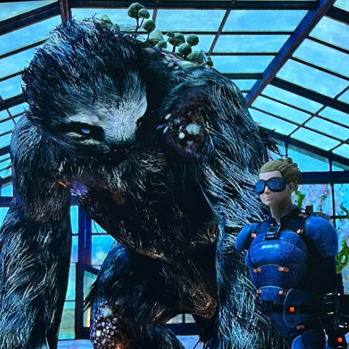 Character Voice Talent, Birmingham, Alabama A picture of a female character in stealth armor from Fallout 76 standing in front of a megasloth to depict character voice talent services.