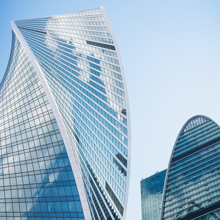 Corporate Messaging Services, Birmingham, Alabama Two high-rise corporate buildings with glass windows reflecting a clear sky to represent corporate messaging services.